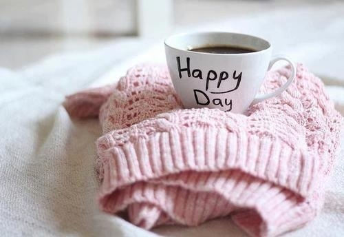 Tasse de café posée sur un gilet rose‑pastel